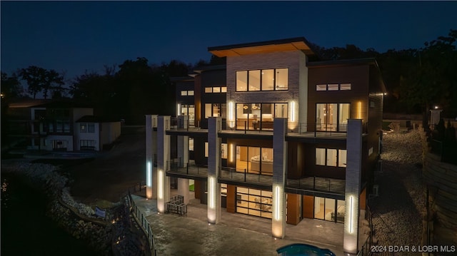 back house at night featuring a balcony