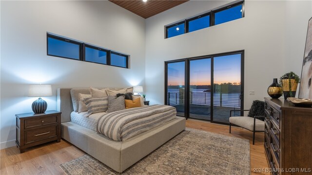 bedroom with a high ceiling, wood ceiling, light wood-type flooring, and access to outside