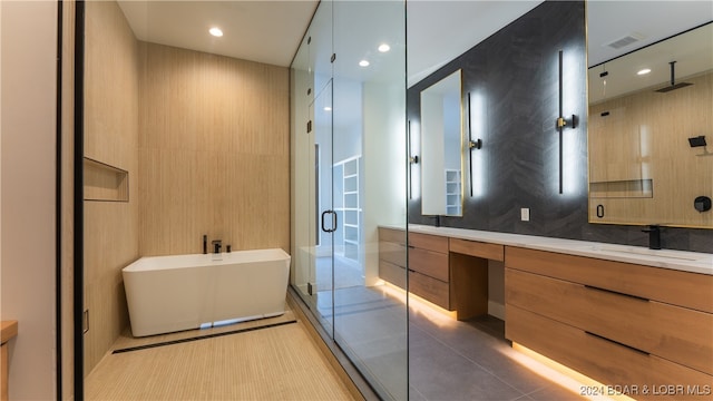 bathroom with tile walls, plus walk in shower, vanity, and tile patterned flooring