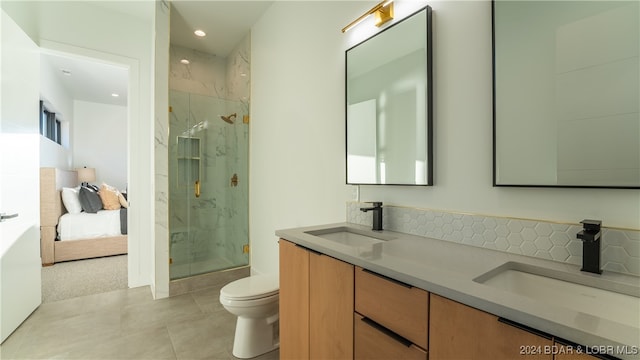 bathroom with tile patterned floors, a shower with door, backsplash, vanity, and toilet