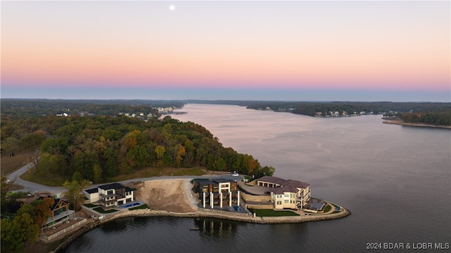 aerial view at dusk featuring a water view