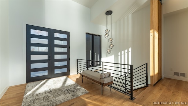 entryway featuring french doors, light wood-type flooring, and a high ceiling