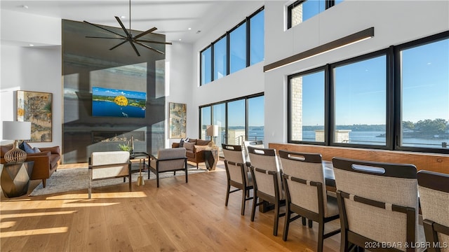 dining area with ceiling fan, light hardwood / wood-style floors, and a towering ceiling