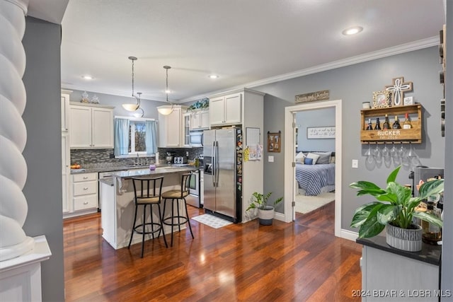 kitchen with appliances with stainless steel finishes, pendant lighting, sink, a breakfast bar area, and a center island