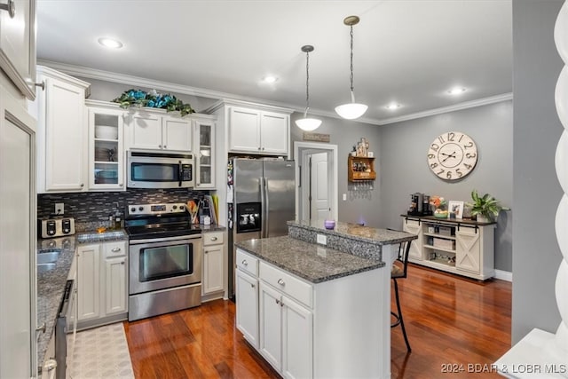 kitchen with dark stone countertops, stainless steel appliances, a kitchen breakfast bar, a center island, and white cabinets