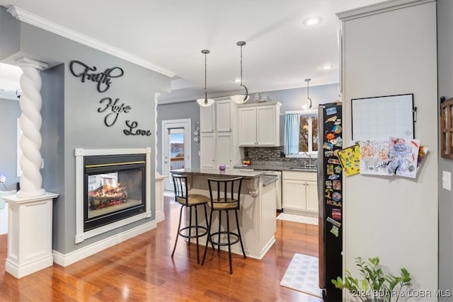 kitchen featuring pendant lighting, crown molding, a breakfast bar area, backsplash, and a kitchen island