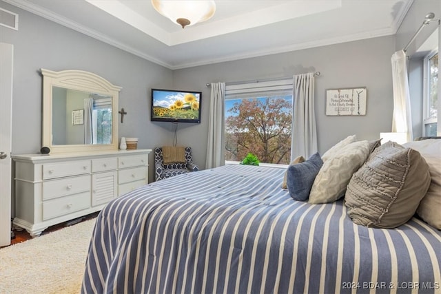 bedroom featuring crown molding, wood-type flooring, and a raised ceiling