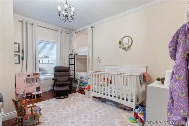 bedroom featuring crown molding, a nursery area, an inviting chandelier, and light hardwood / wood-style floors