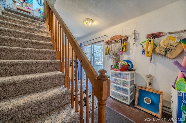 stairs with a textured ceiling and baseboard heating