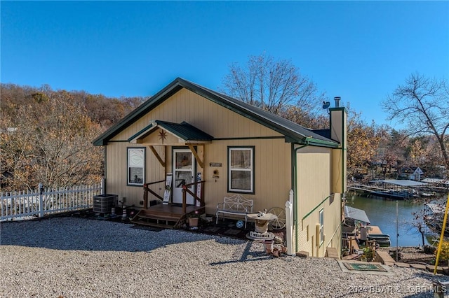 view of front of house featuring a water view, fence, a chimney, and a boat dock