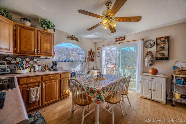 dining area featuring ceiling fan, sink, a textured ceiling, and light wood-type flooring