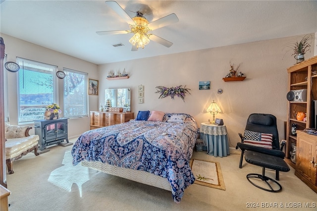 carpeted bedroom with ceiling fan and a wood stove