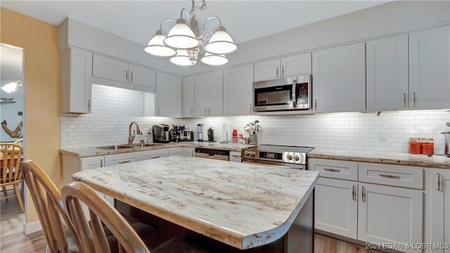 kitchen featuring pendant lighting, stainless steel appliances, sink, and white cabinets