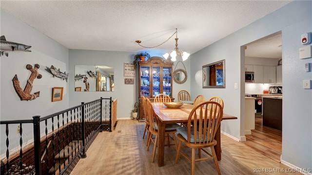 dining area featuring a textured ceiling, light hardwood / wood-style floors, and a chandelier