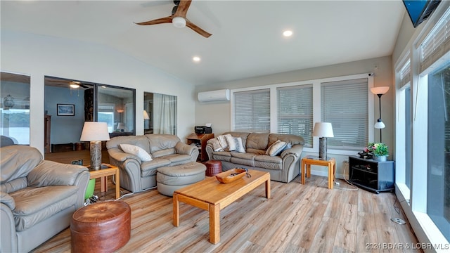 living room with ceiling fan, vaulted ceiling, a wall mounted AC, and light wood-type flooring