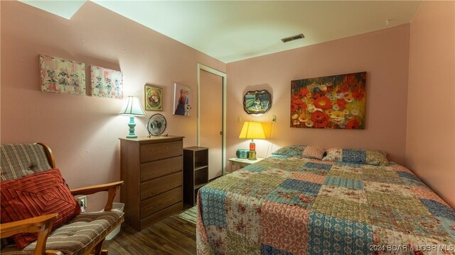 bedroom with dark hardwood / wood-style floors and a closet