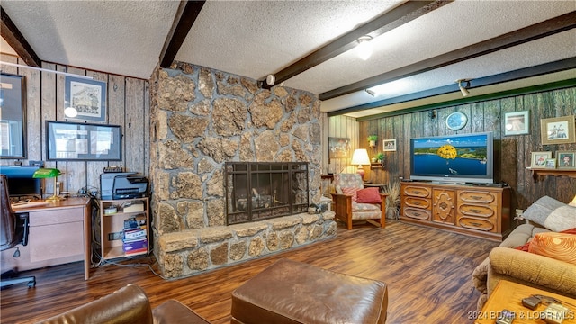 living room with a stone fireplace, wood-type flooring, a textured ceiling, and beamed ceiling