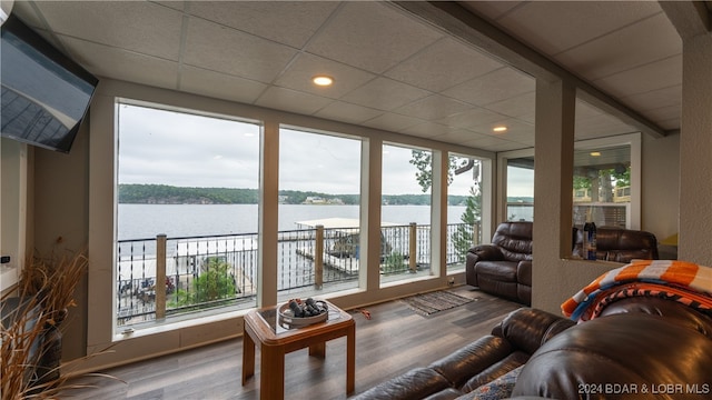 sunroom / solarium featuring a water view and a paneled ceiling