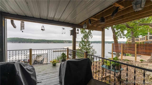 wooden terrace featuring a water view and a grill