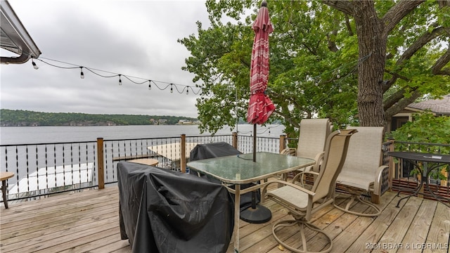 wooden deck featuring a water view and a grill