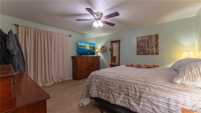 bedroom with ceiling fan, a textured ceiling, and light wood-type flooring