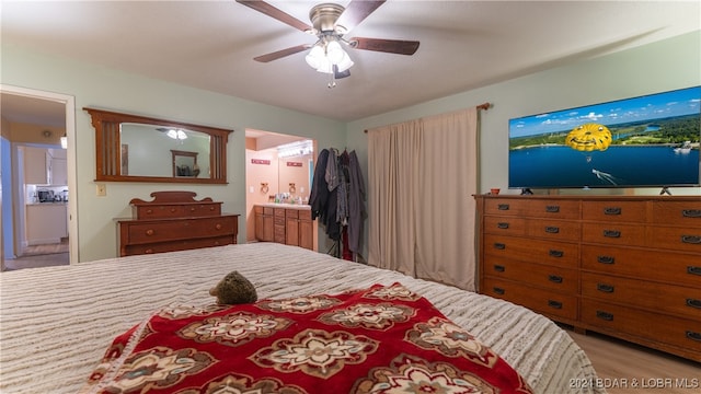 bedroom with ensuite bathroom, ceiling fan, and light hardwood / wood-style flooring