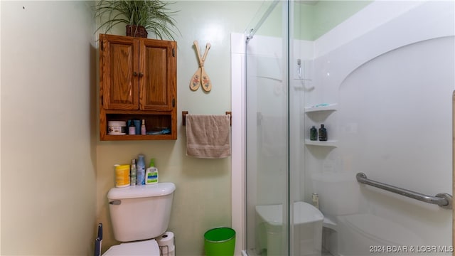 bathroom featuring a shower with shower door and toilet