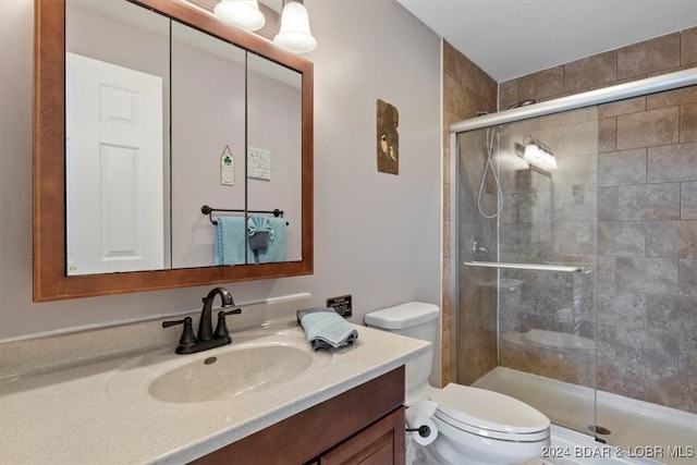 bathroom featuring a shower with door, vanity, and toilet