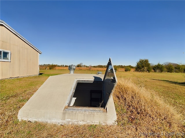 entry to storm shelter featuring a rural view