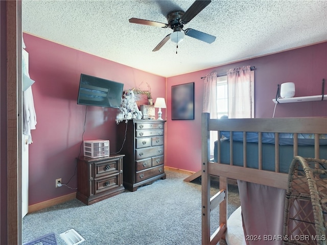 bedroom with a textured ceiling, light colored carpet, and ceiling fan