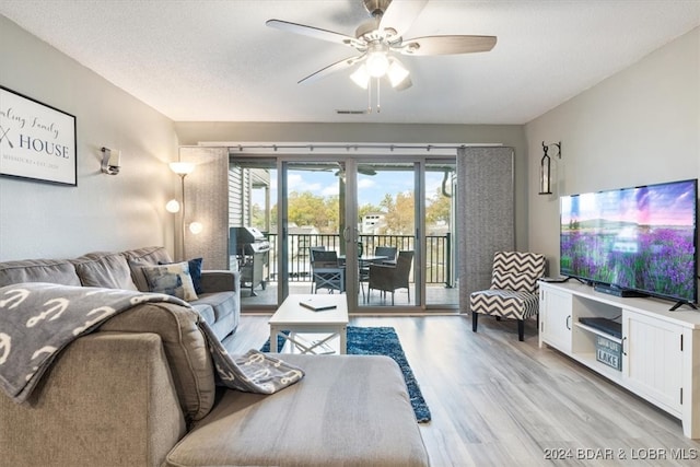 living room with a textured ceiling, french doors, light hardwood / wood-style floors, and ceiling fan