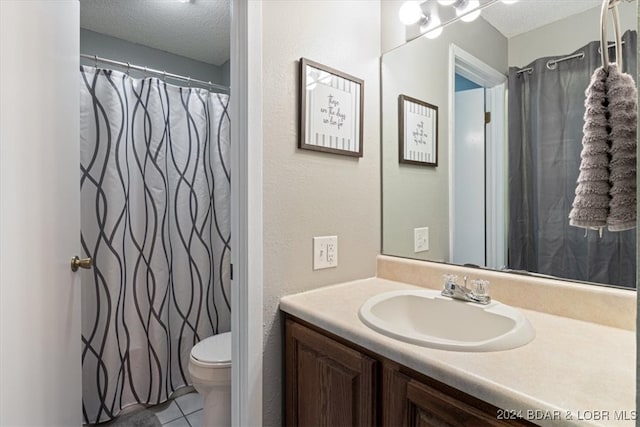 bathroom featuring vanity, tile patterned floors, a textured ceiling, and toilet