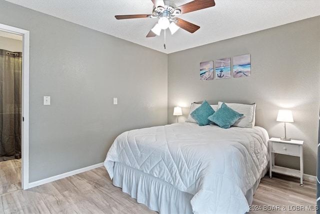 bedroom with a textured ceiling, light hardwood / wood-style flooring, and ceiling fan