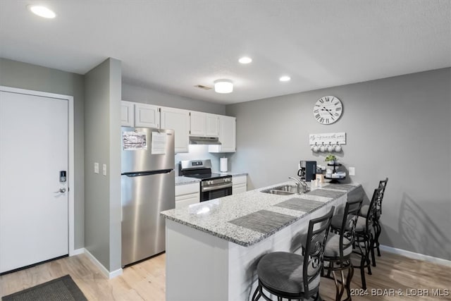 kitchen with stainless steel appliances, light wood-type flooring, white cabinetry, a breakfast bar, and kitchen peninsula