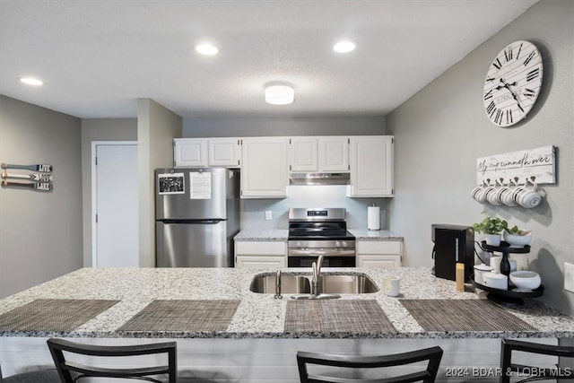 kitchen with white cabinetry, sink, a kitchen bar, and stainless steel appliances