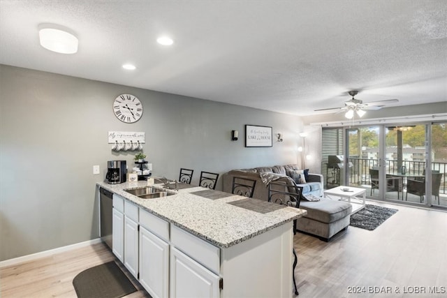 kitchen with white cabinetry, sink, light hardwood / wood-style floors, a breakfast bar, and ceiling fan