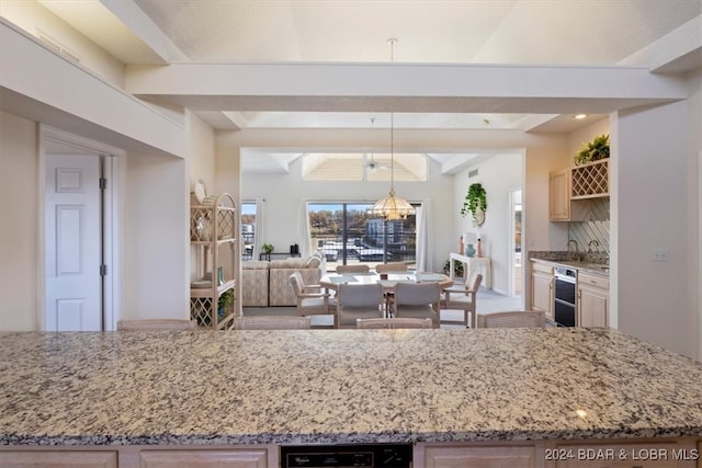 kitchen with beamed ceiling, hanging light fixtures, and light stone counters