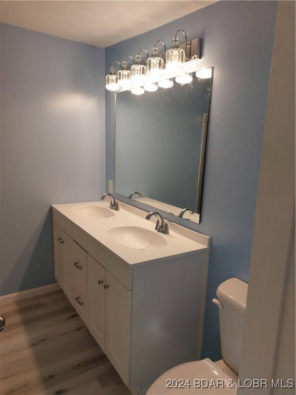 bathroom with wood-type flooring, toilet, and vanity