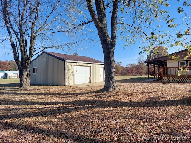 view of yard featuring a garage, an outdoor structure, and a wooden deck