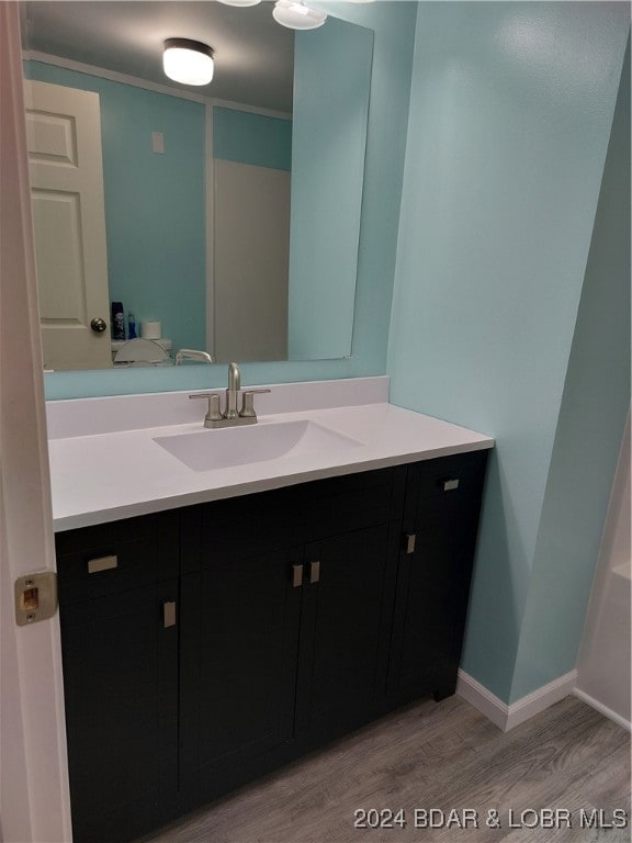 bathroom featuring vanity, wood-type flooring, and ornamental molding