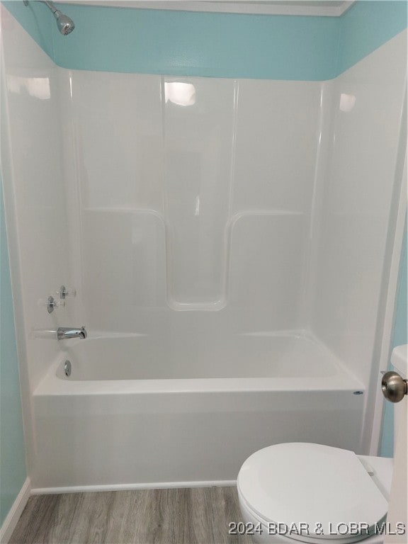 bathroom featuring wood-type flooring, toilet, and bathtub / shower combination