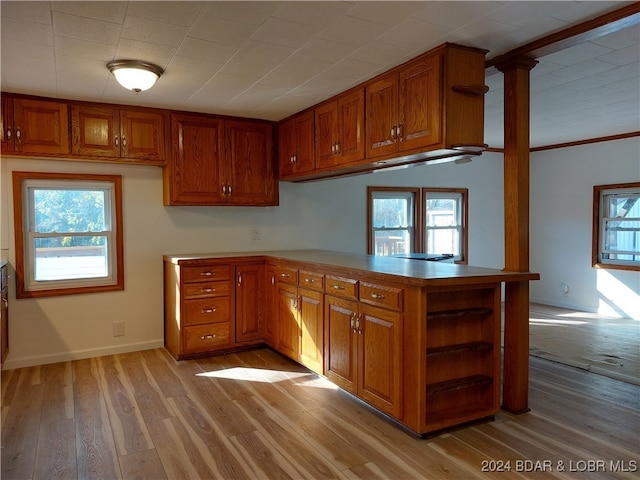 kitchen featuring ornamental molding, kitchen peninsula, plenty of natural light, and light wood-type flooring