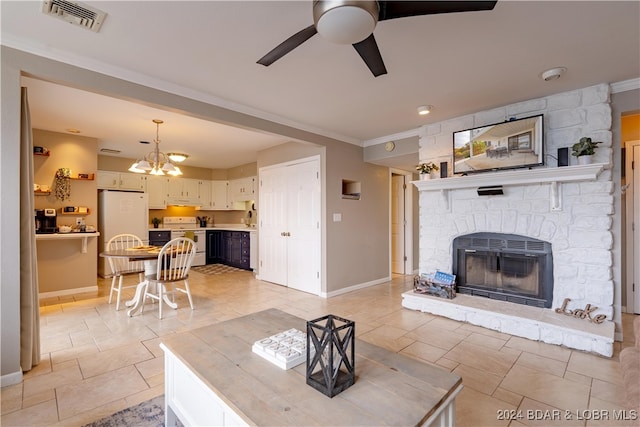 living room featuring ceiling fan with notable chandelier, a stone fireplace, and ornamental molding