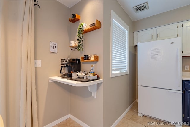 kitchen featuring white cabinetry, light tile patterned floors, and white refrigerator