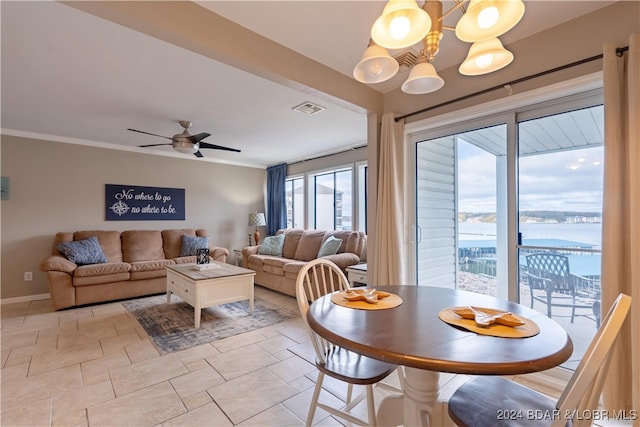 dining room with ceiling fan with notable chandelier, a water view, and crown molding