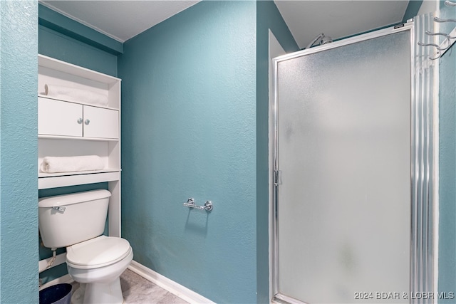 bathroom featuring tile patterned floors, toilet, and a shower with shower door