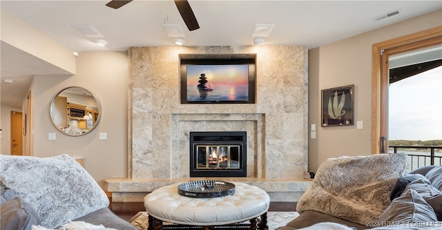 living room featuring a premium fireplace and ceiling fan