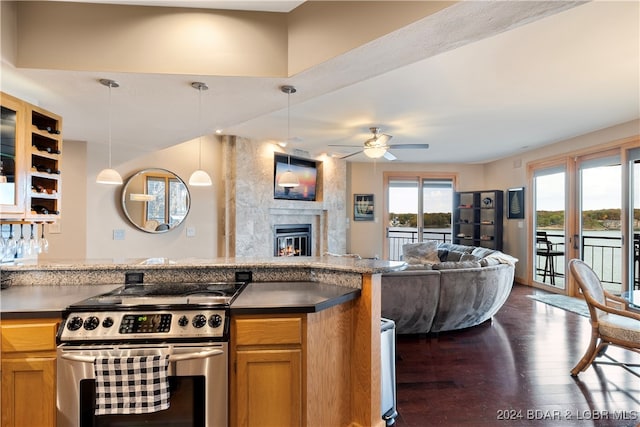 kitchen featuring pendant lighting, ceiling fan, a fireplace, stainless steel range oven, and dark hardwood / wood-style flooring