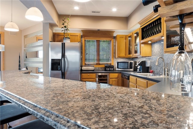 kitchen featuring pendant lighting, sink, backsplash, a kitchen breakfast bar, and stainless steel appliances