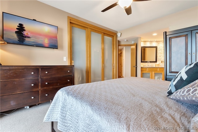 carpeted bedroom featuring sink, ensuite bath, and ceiling fan